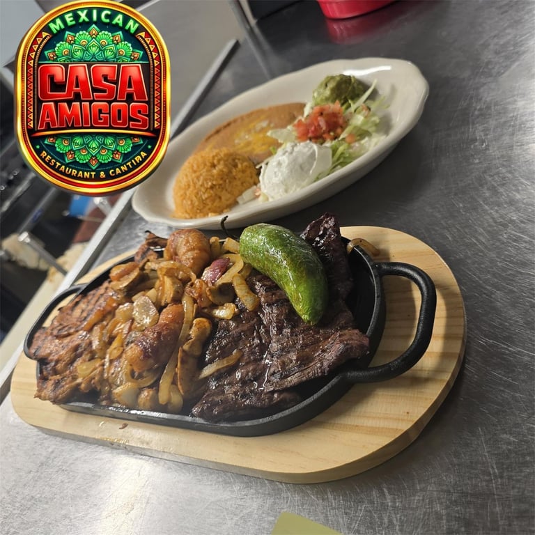 Casa Amigos Mexican restaurant sizzling steak fajitas with grilled peppers and onions, served with rice and a soft taco on a wooden board