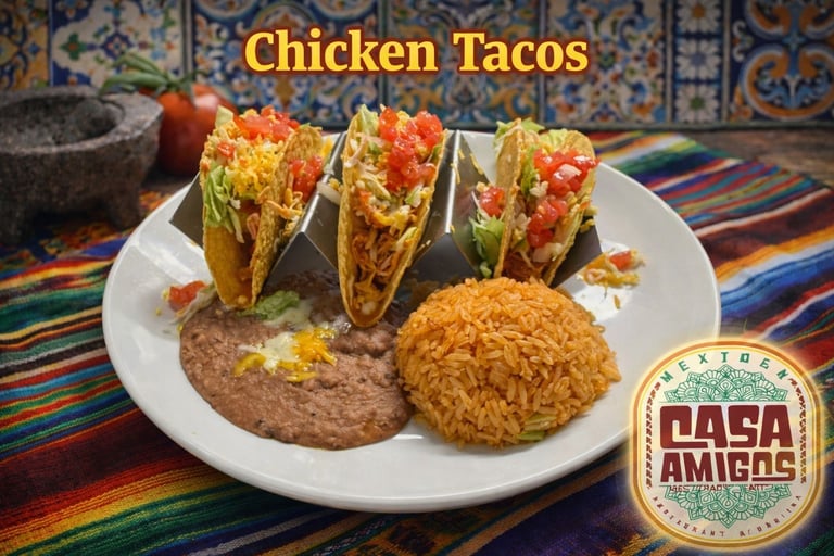 Plate of chicken tacos with refried beans and spanish rice on colorful striped cloth with Casa Amigos logo